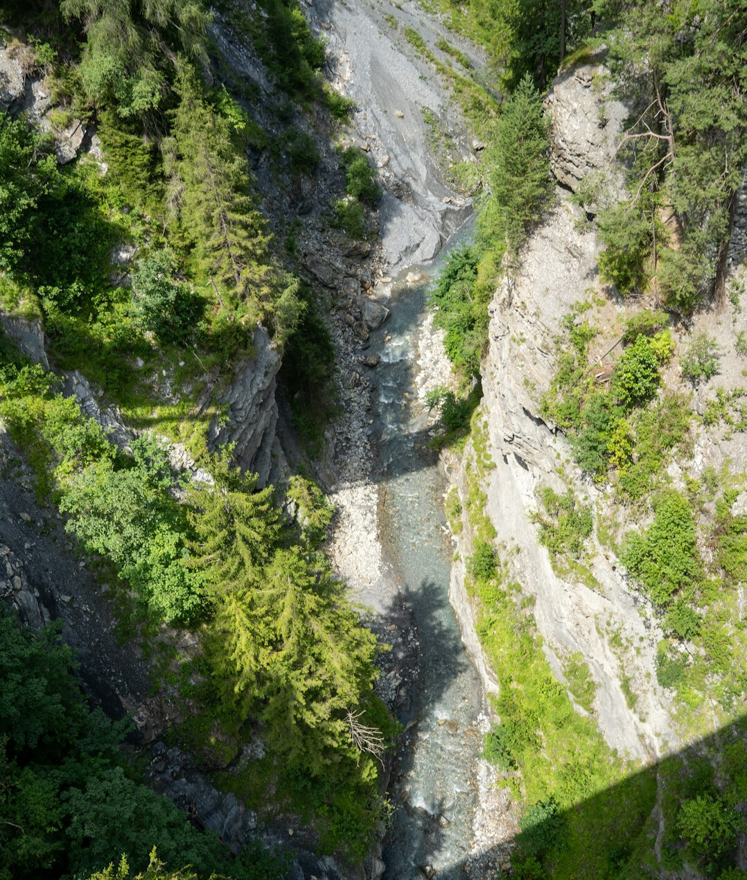 Swiss alpine river valley with an industrial pipe discharging into the water